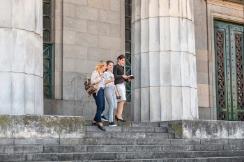 Drei Studierende gehen eine Universitätstreppe hinunter