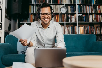 Student sitzt in seinem Wohnzimmer am Laptop