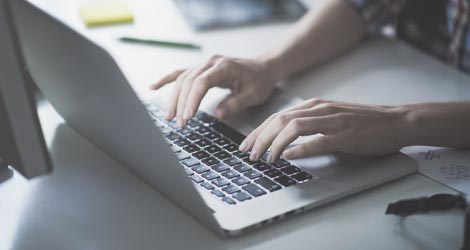 Bildausschnitt zeigt Laptop, auf dem eine Person etwas tippt