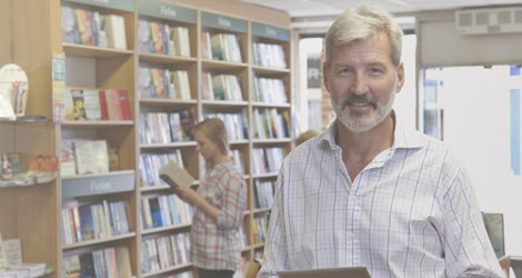 Älterer Mann steht in einer Buchhandlung