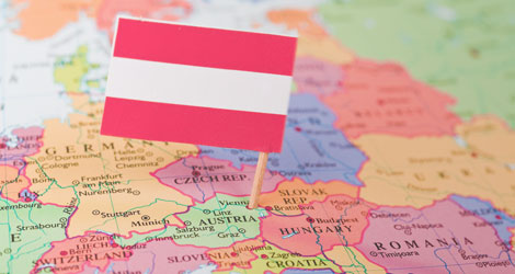 Bildausschnitt zeigt Teil von Europa auf einer Weltkarte, ein Zahnstocher mit der österreichischen Flagge steckt an der Position von Österreich