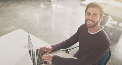 Student sitzt am Tisch und tippt etwas auf seinem Laptop