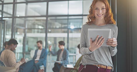 Studentin im Universitätsgebäude, im Hintergrund sitzen ihre Kommilitonen